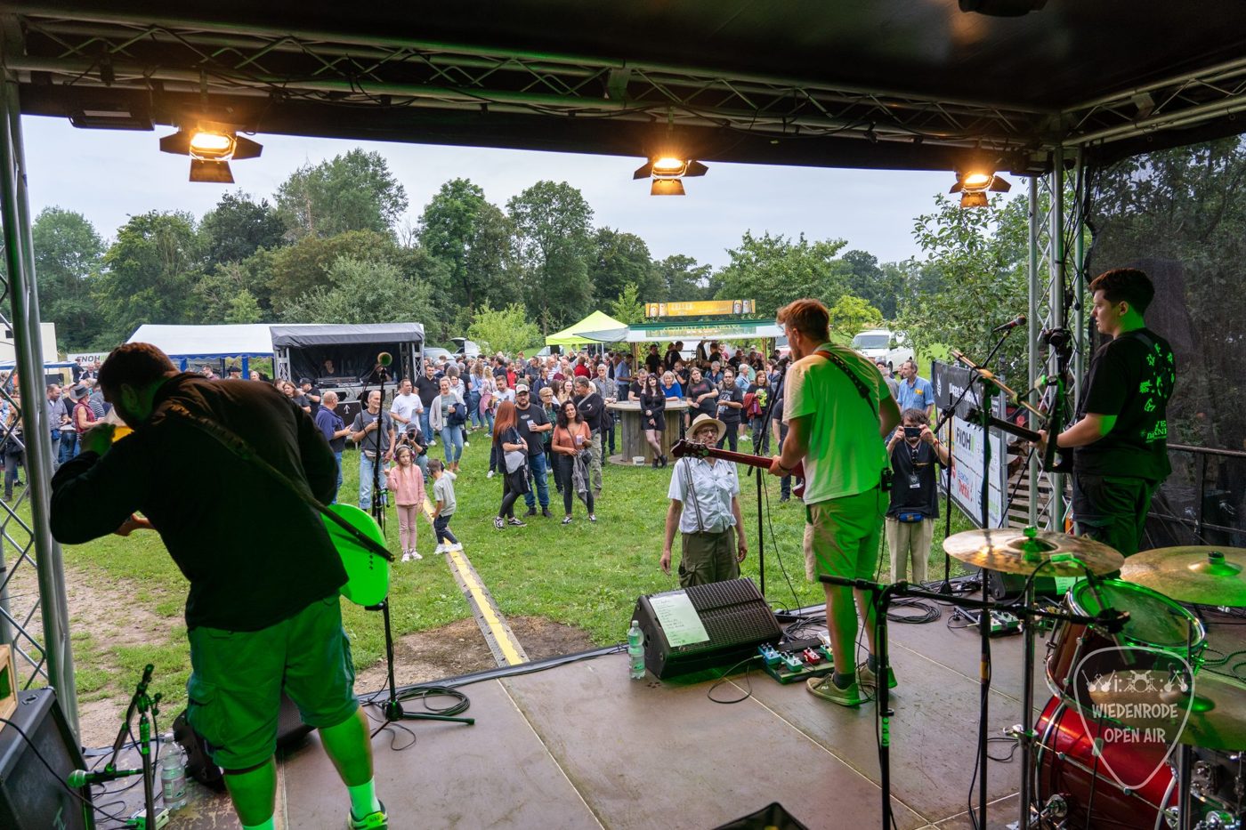 Band auf der Bühne mit Blick über die Festivalwiese und das Publikum bei Tageslicht