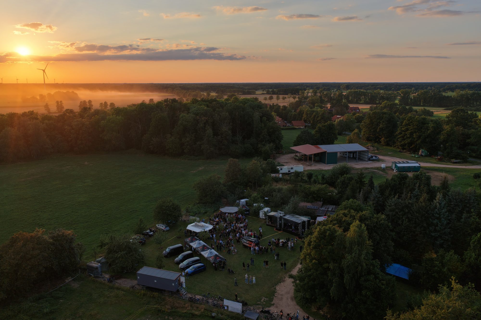 Luftbild von Wiedenrode mit Festivalgelände, Feldern und Wald bei Sonnenuntergang